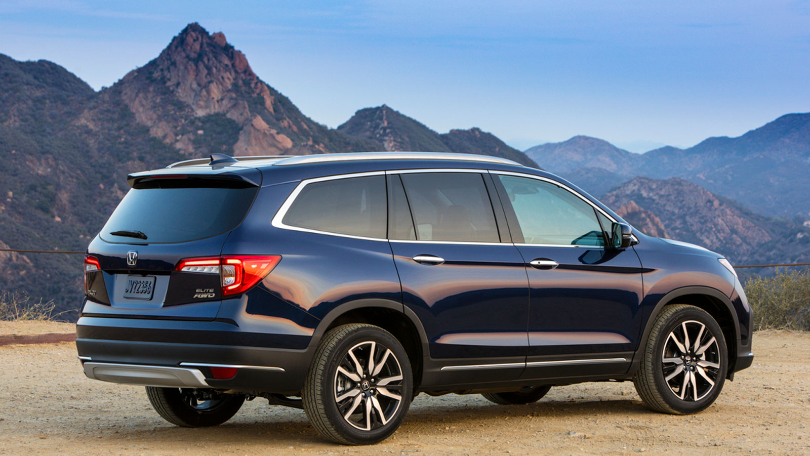 A photo of a navy blue Honda Passport crossover with mountains behind. 