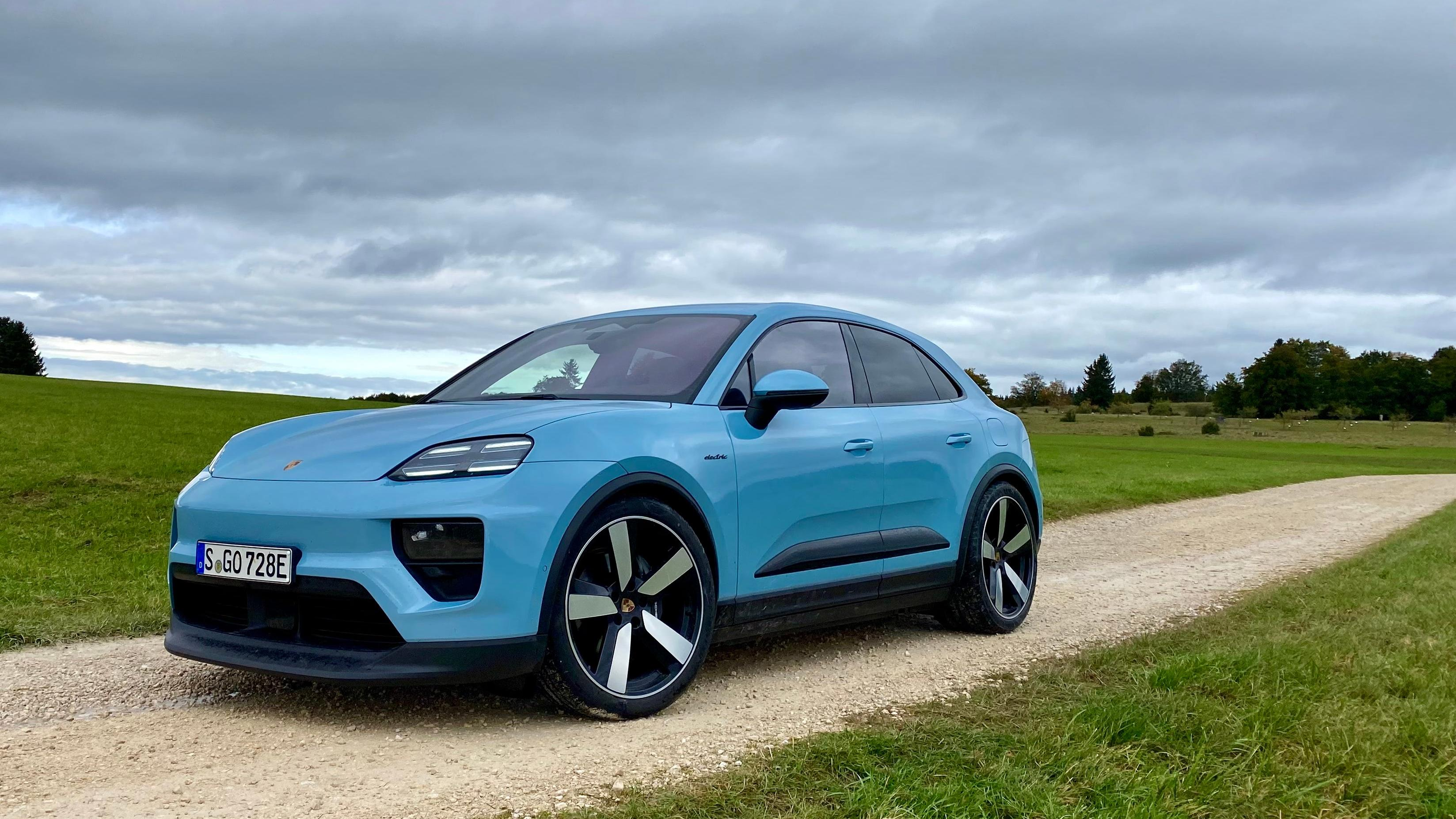 Front three quarters of the light blue Macan base on a gravel trail in a field