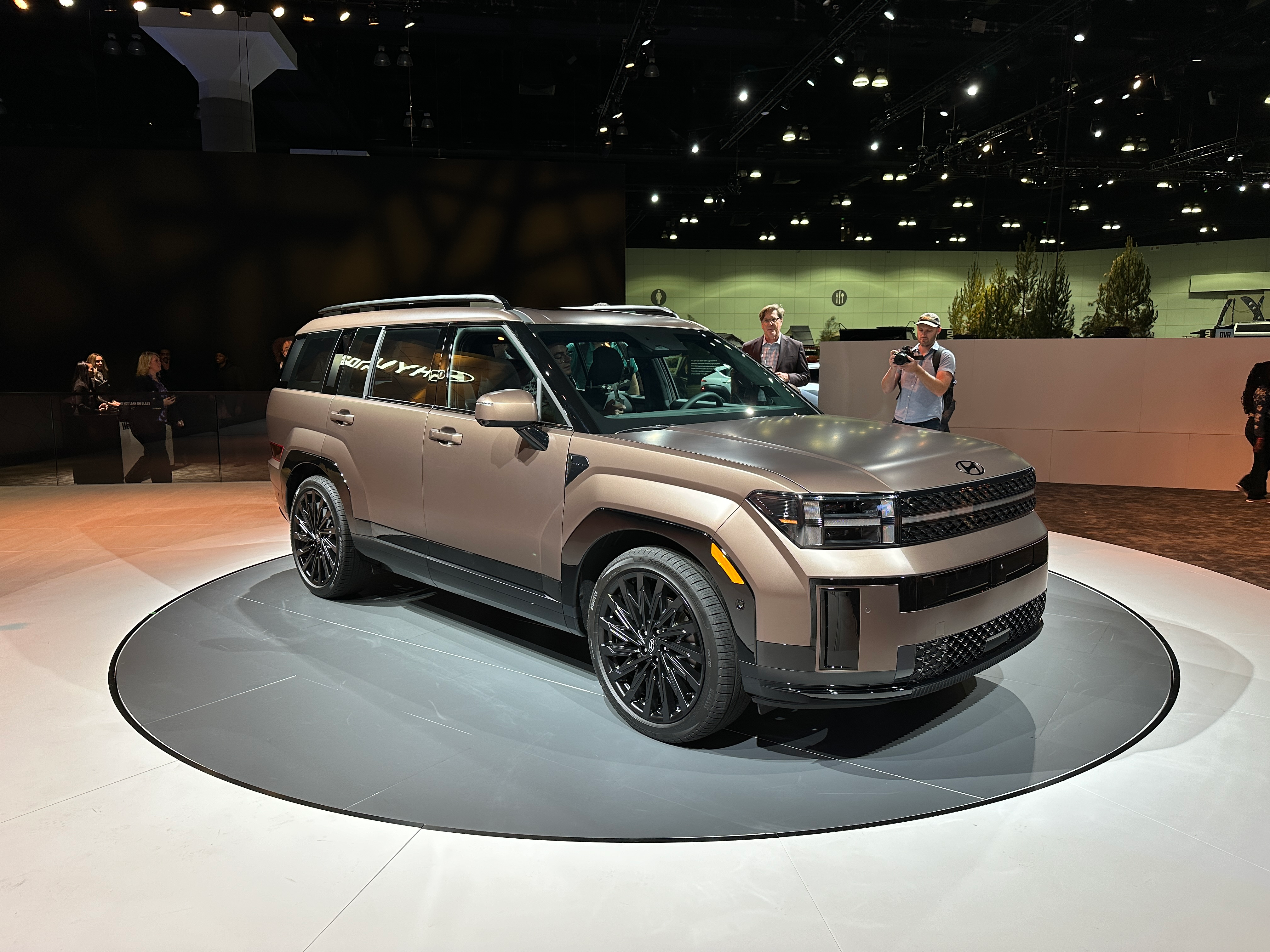 Front 3/4 view of a matte bronze Hyundai Santa Fe at an auto show