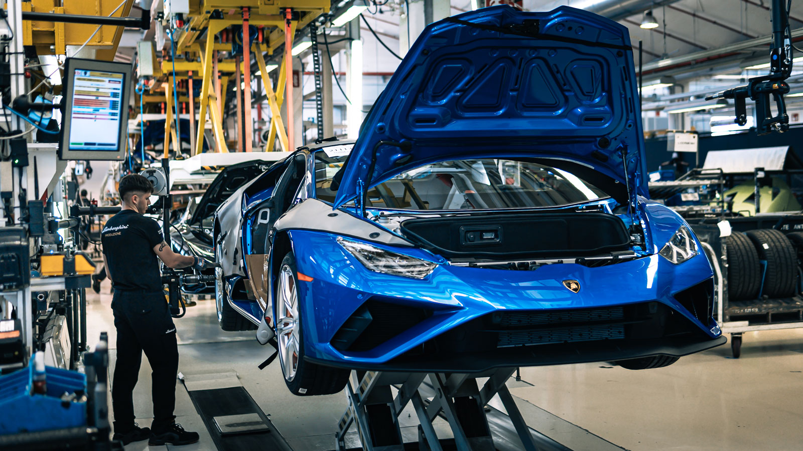 A photo of a blue Lamborghini supercar being assembled at a factory. 