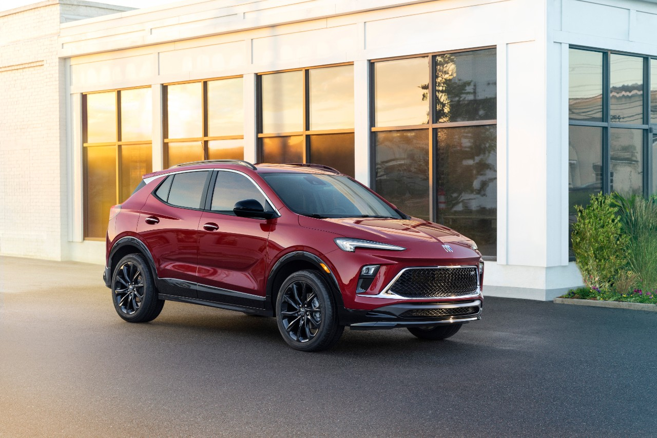 A Buick Encore GX in red parked in front of a building