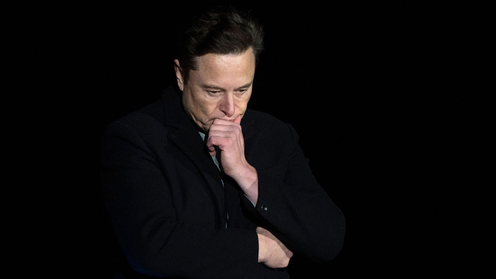 A photo of Elon Musk with his hand on his chin. 