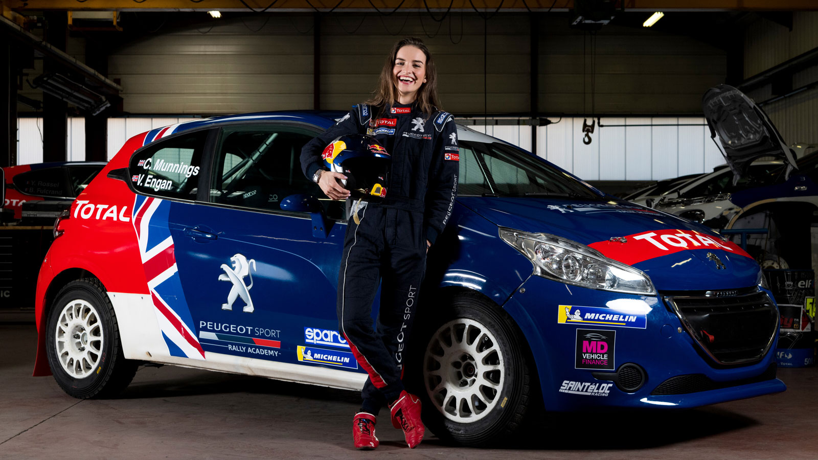 Rally driver Catie Munnings poses next to a car. 