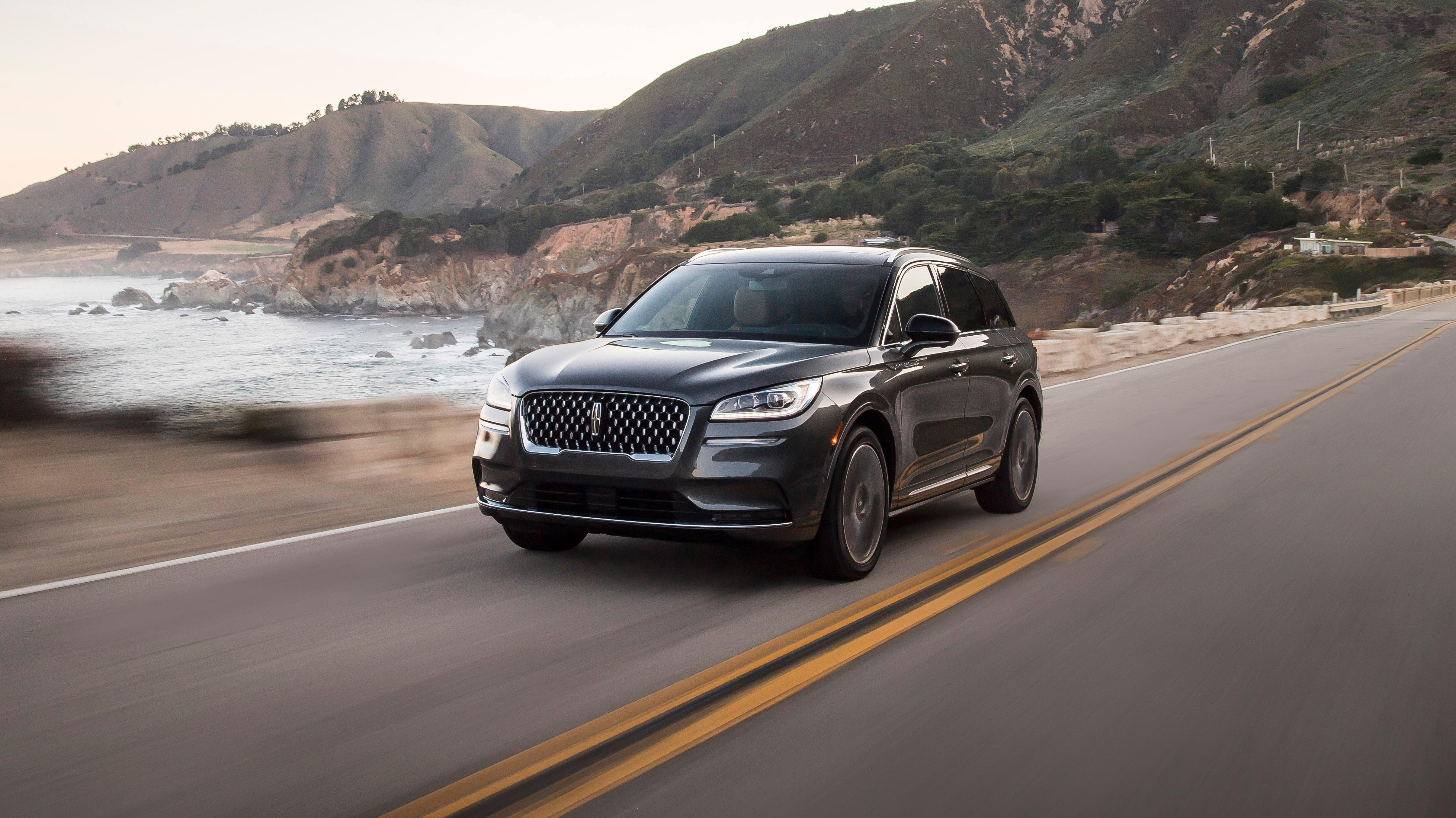 A dark grey Lincoln Corsair driving down a scenic seaside road.