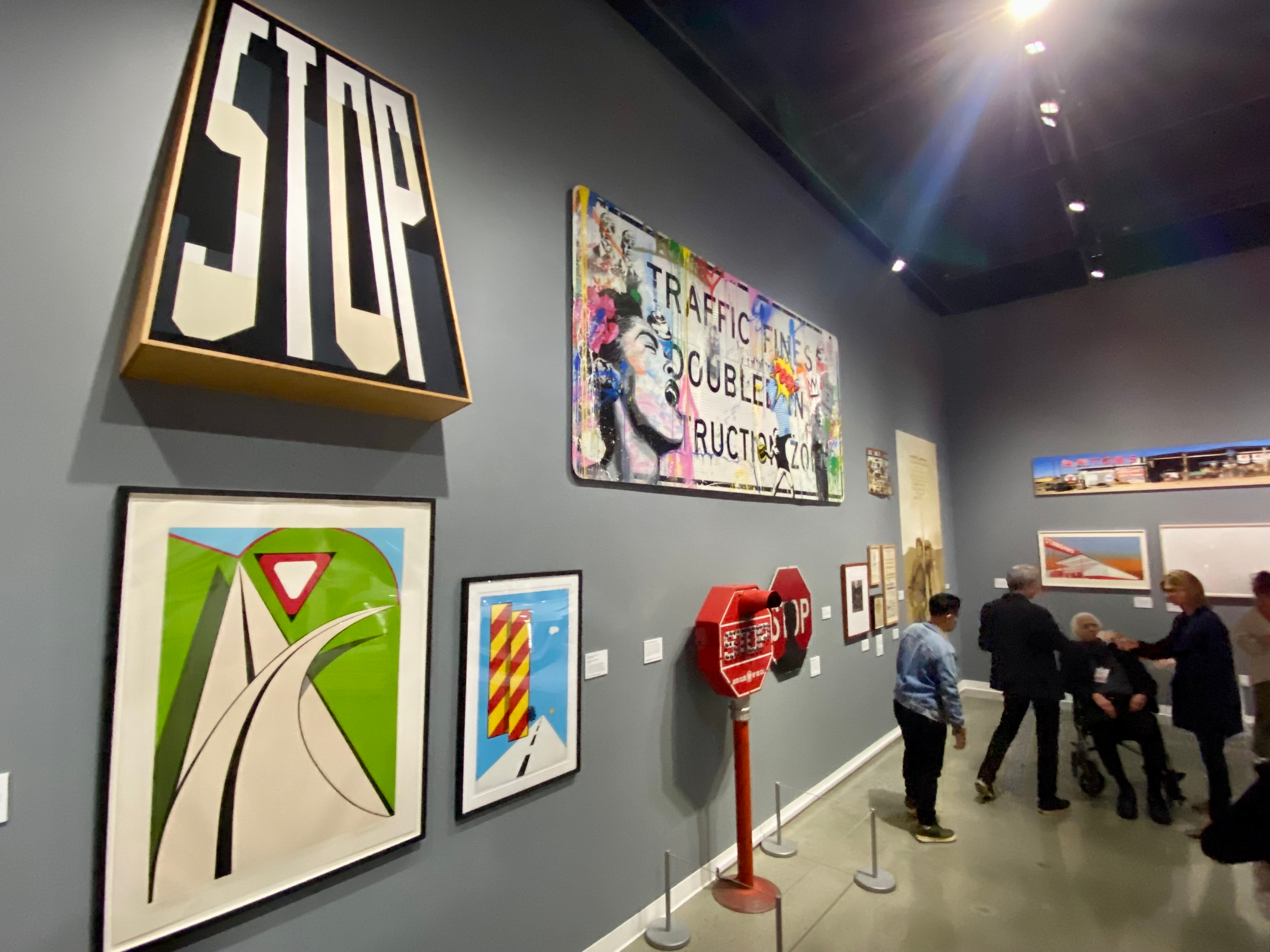 A photo of the sign section of the exhibit, showing some historical road signs and some artistic interpretations of street signs.