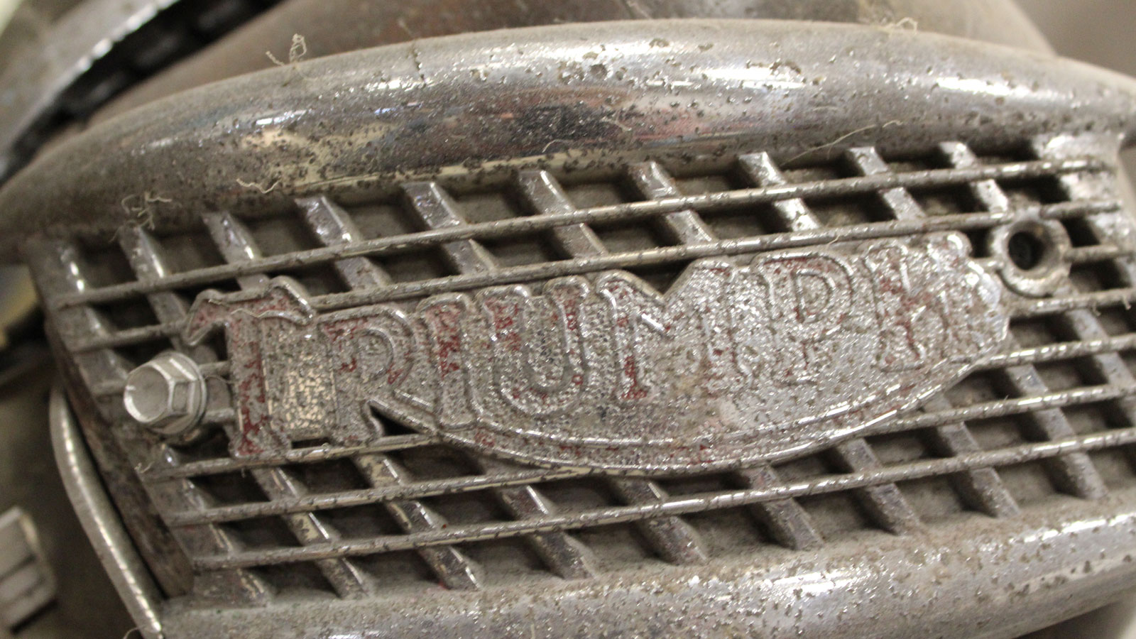 A close up photo of a rusty Triumph name badge. 