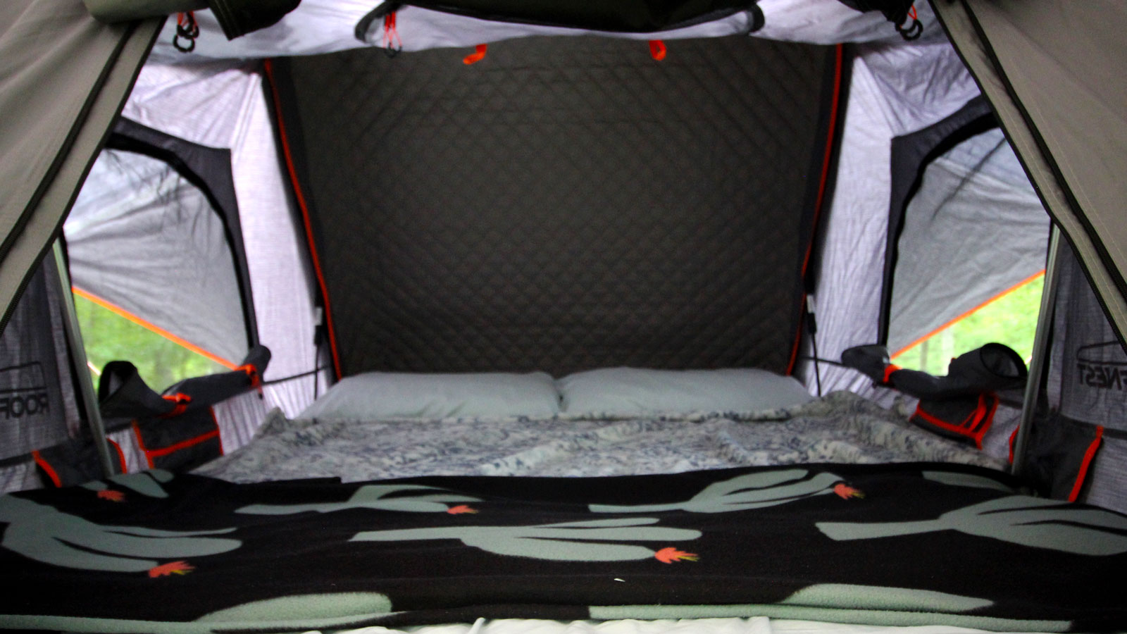 A photo of the inside area of a Roofnest Condor tent made up with bedding. 