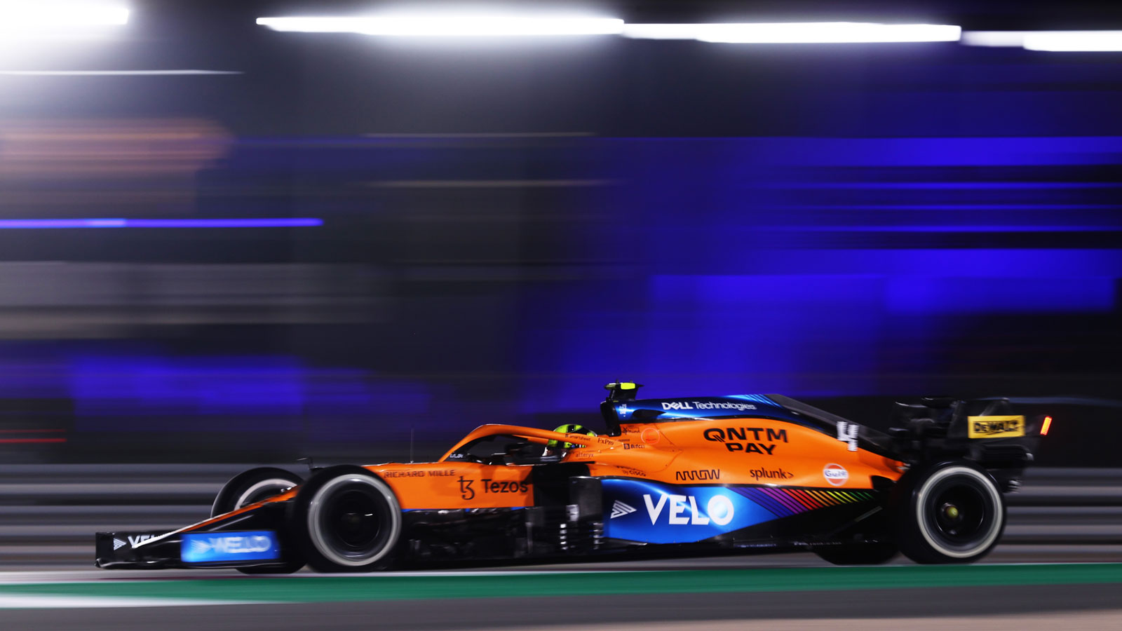 A photo of a McLaren Formula 1 car racing at night. 