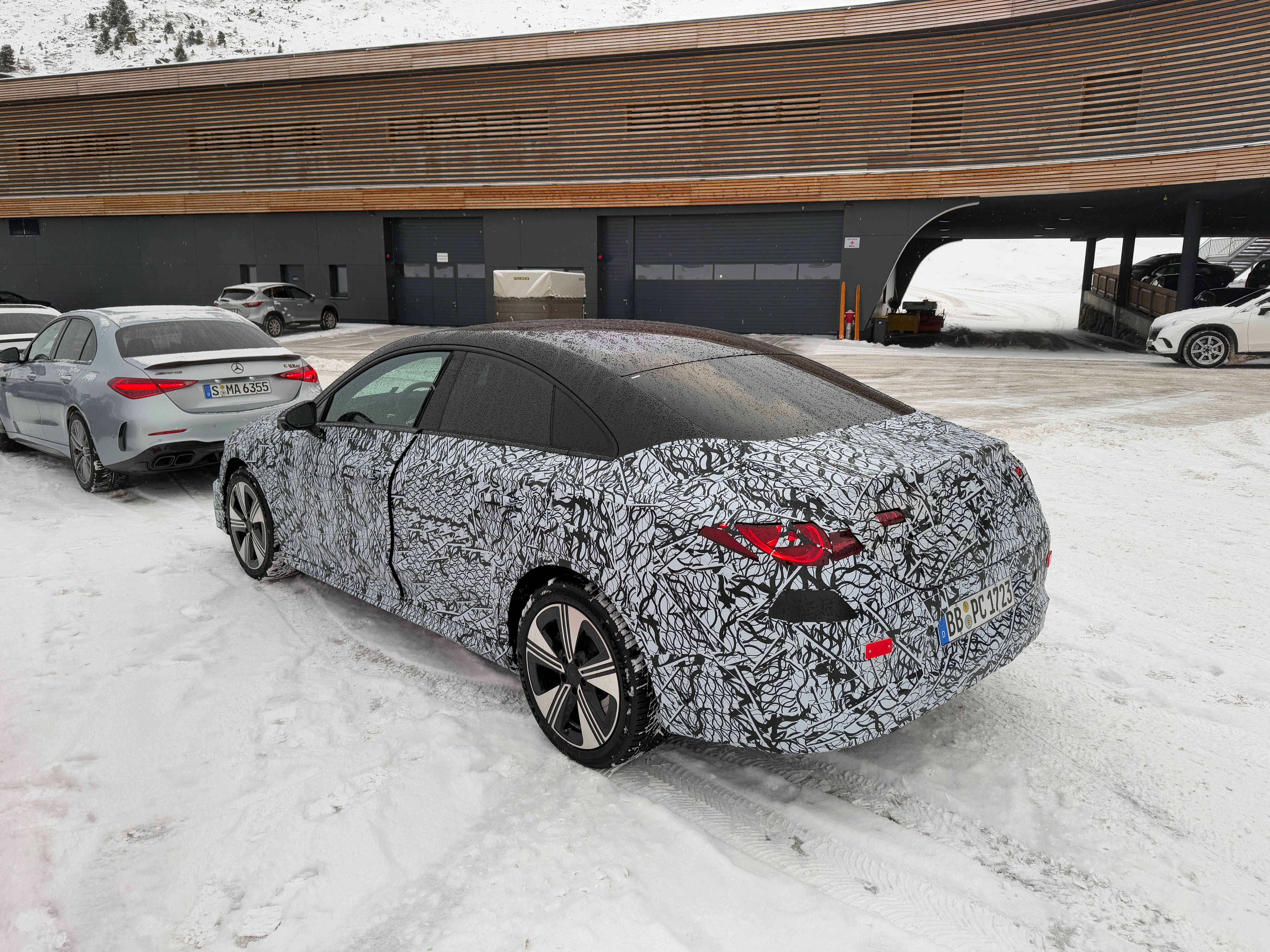 Rear 3/4 view of a camouflaged Mercedes-Benz CLA EV prototype