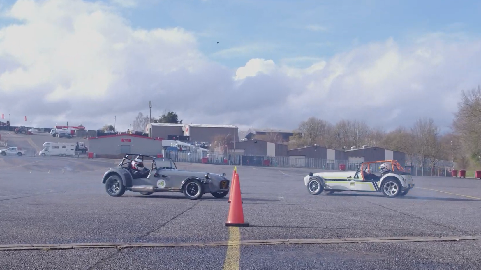 A photo of two Caterham cars drifting on a track. 