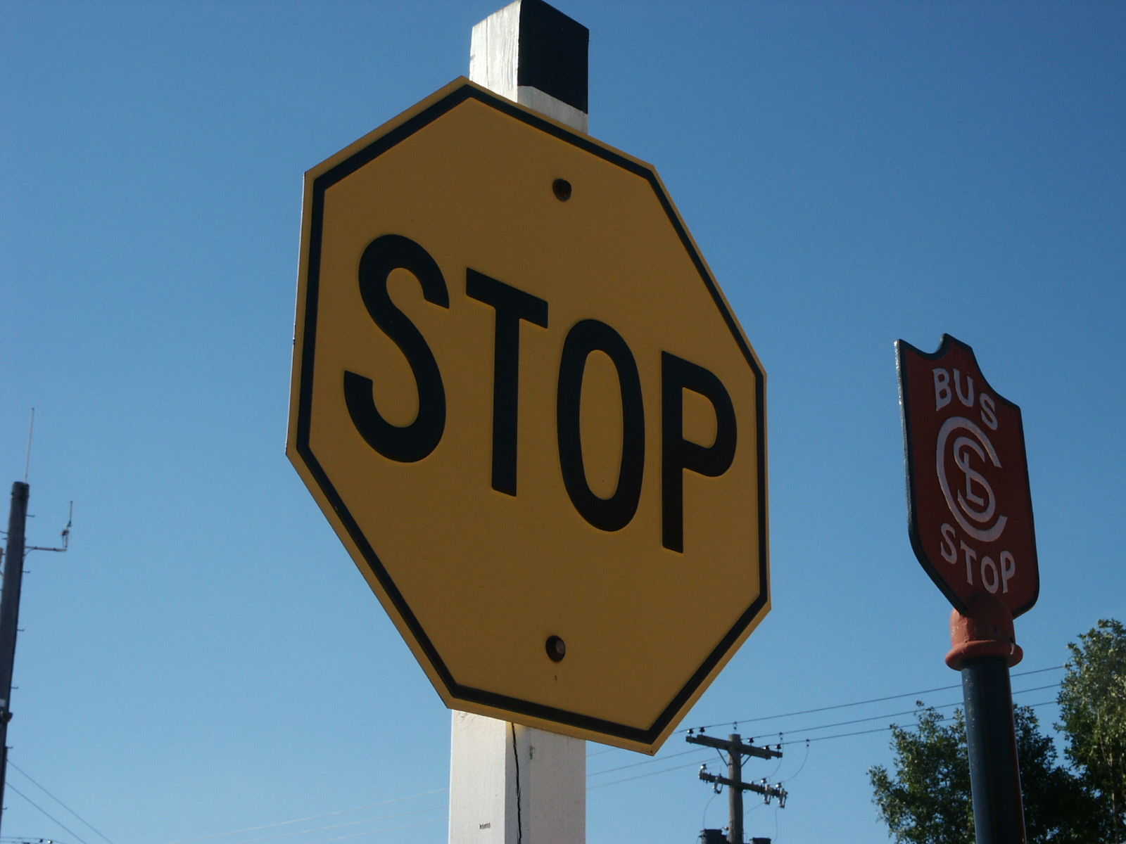 A recreation of a vintage black text on yellow background stop sign.