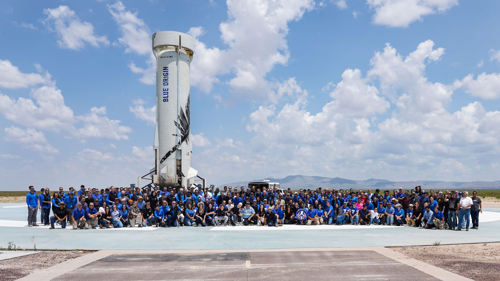 The Blue Origin team gather around a space rocket 