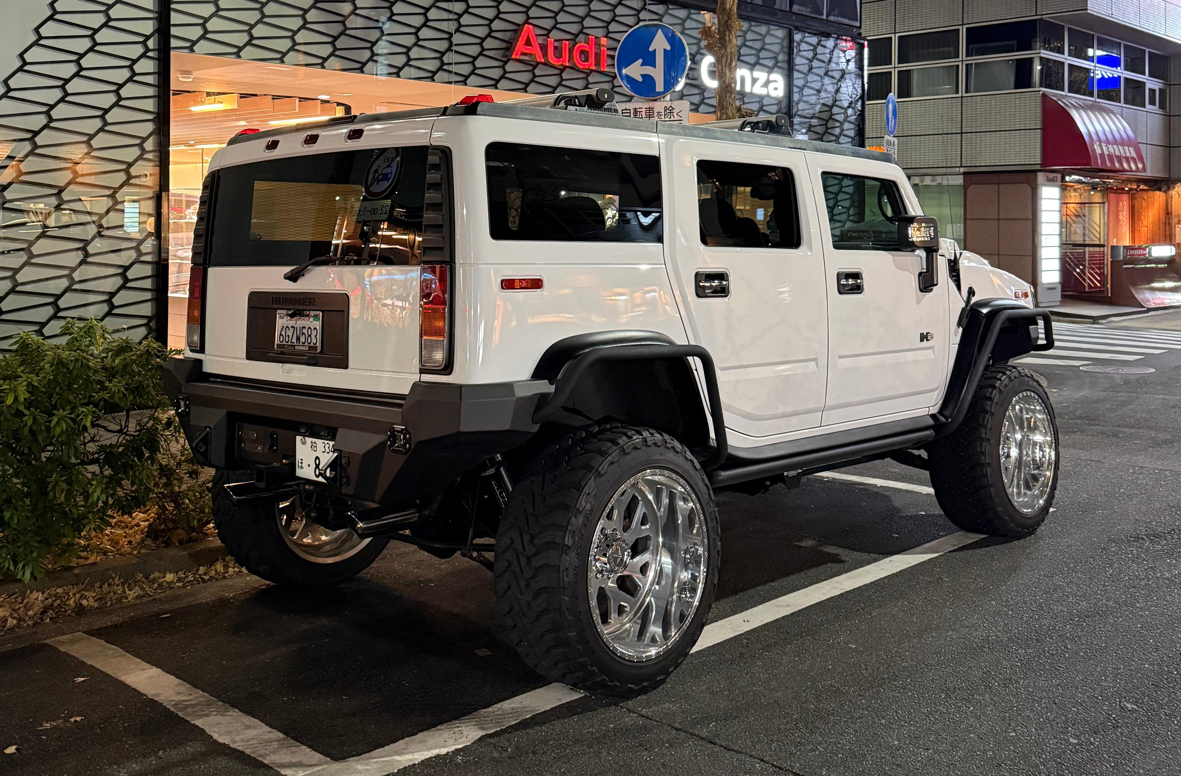 Rear 3/4 view of a lifted white Hummer H2