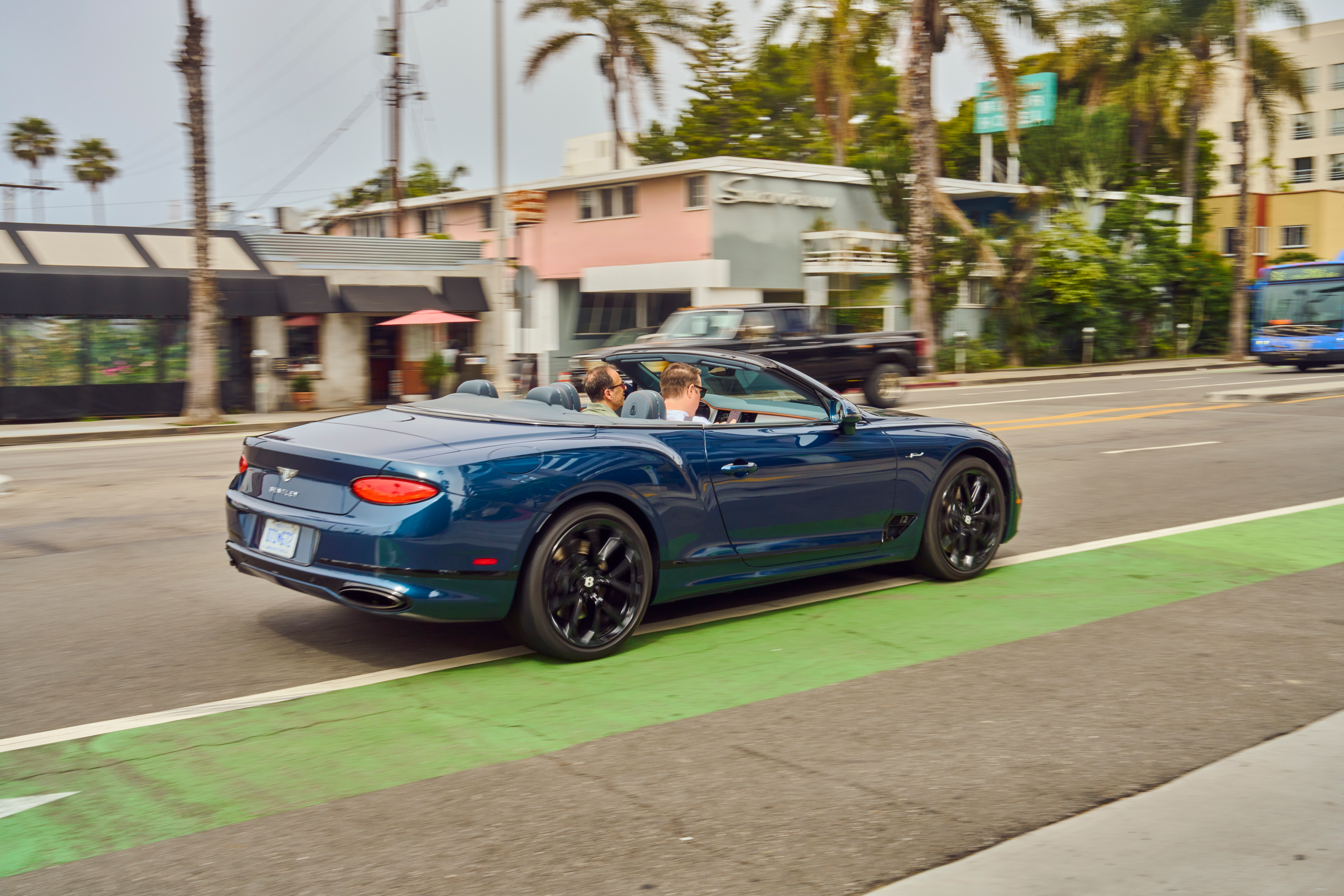 A blue Bentley Continental GT/C W12 Speed drives off, top-down.