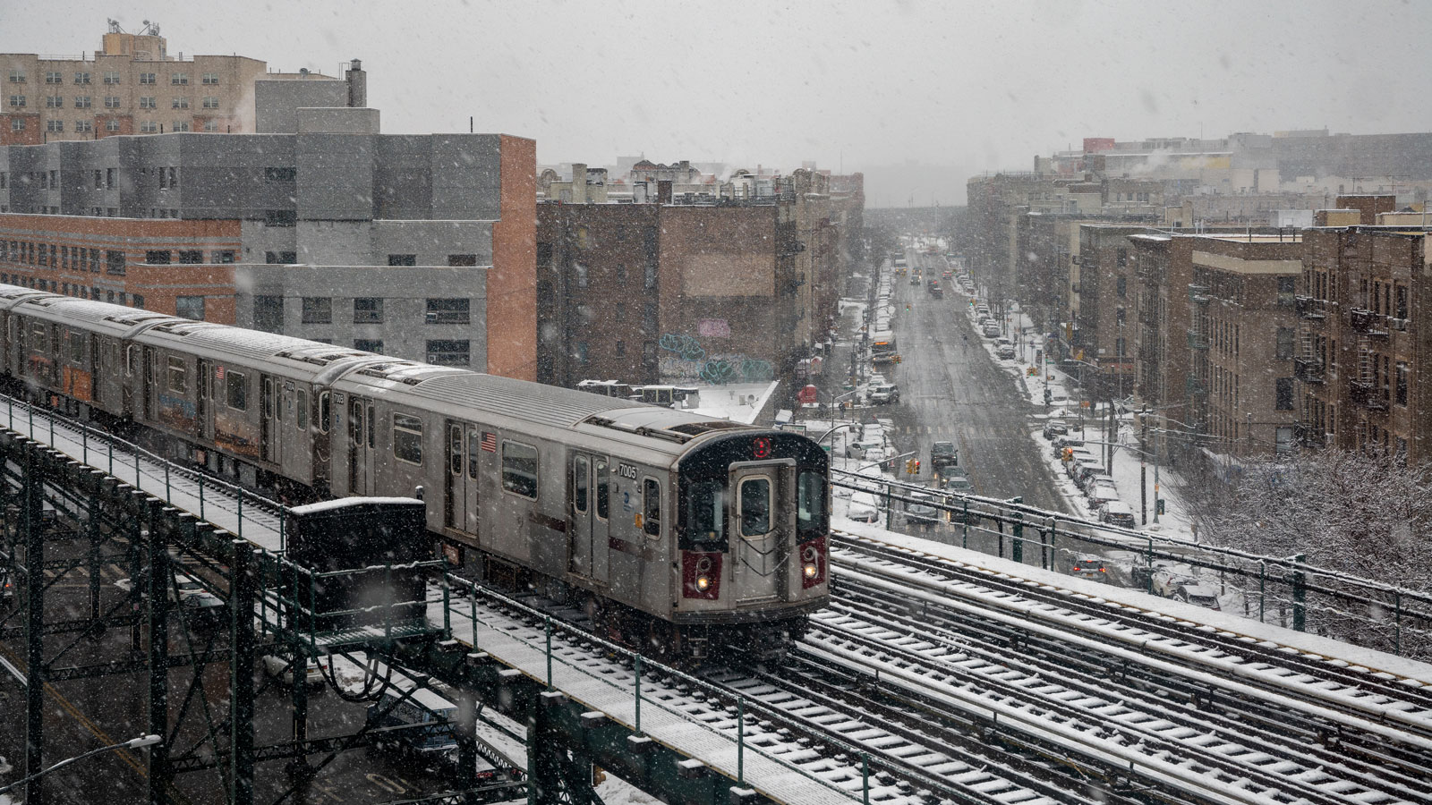 A photo of a subway train driving over a street in The Bronx. 