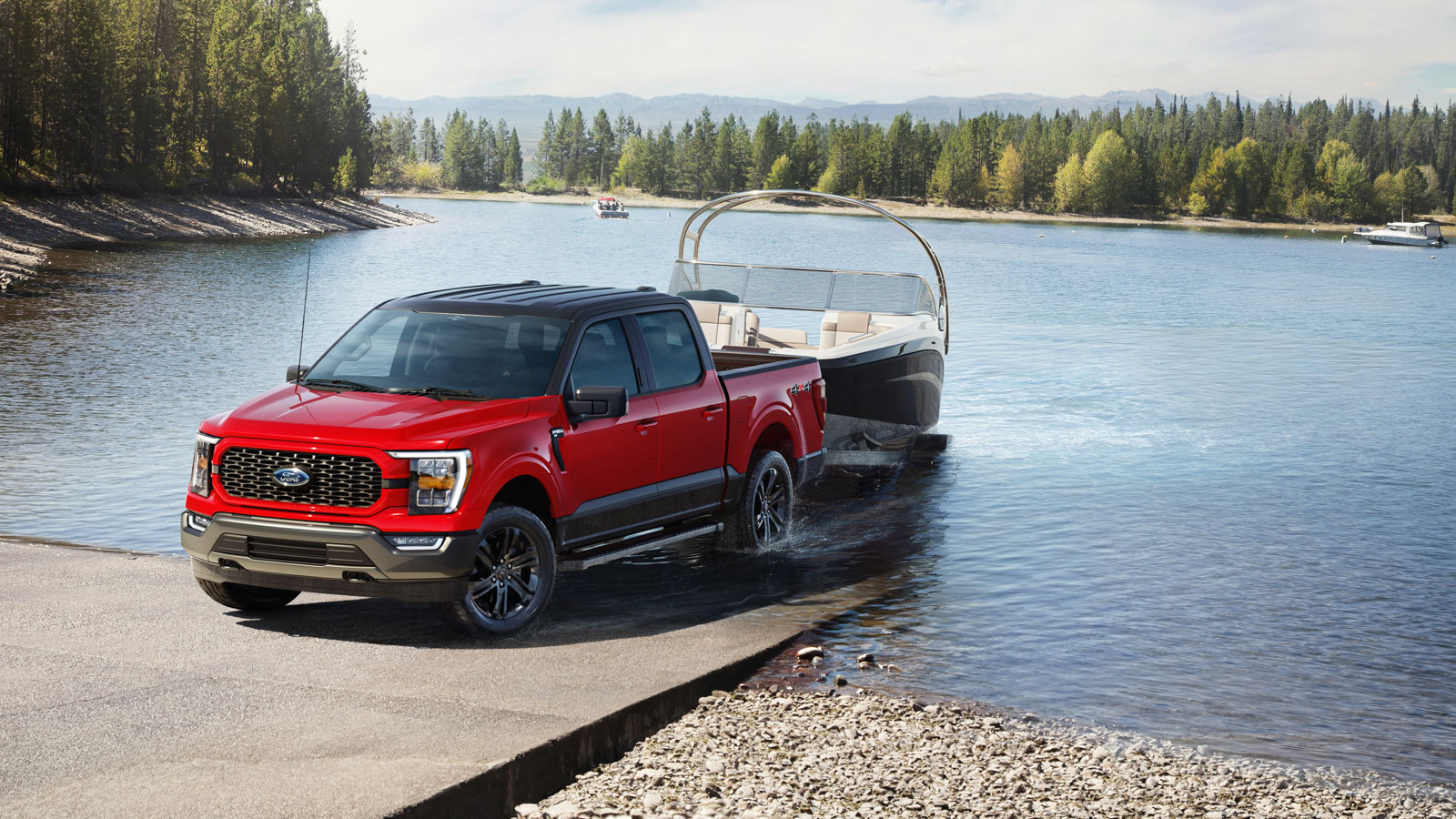 A photo of a red Ford F-150 truck pulling a boat out a lake. 