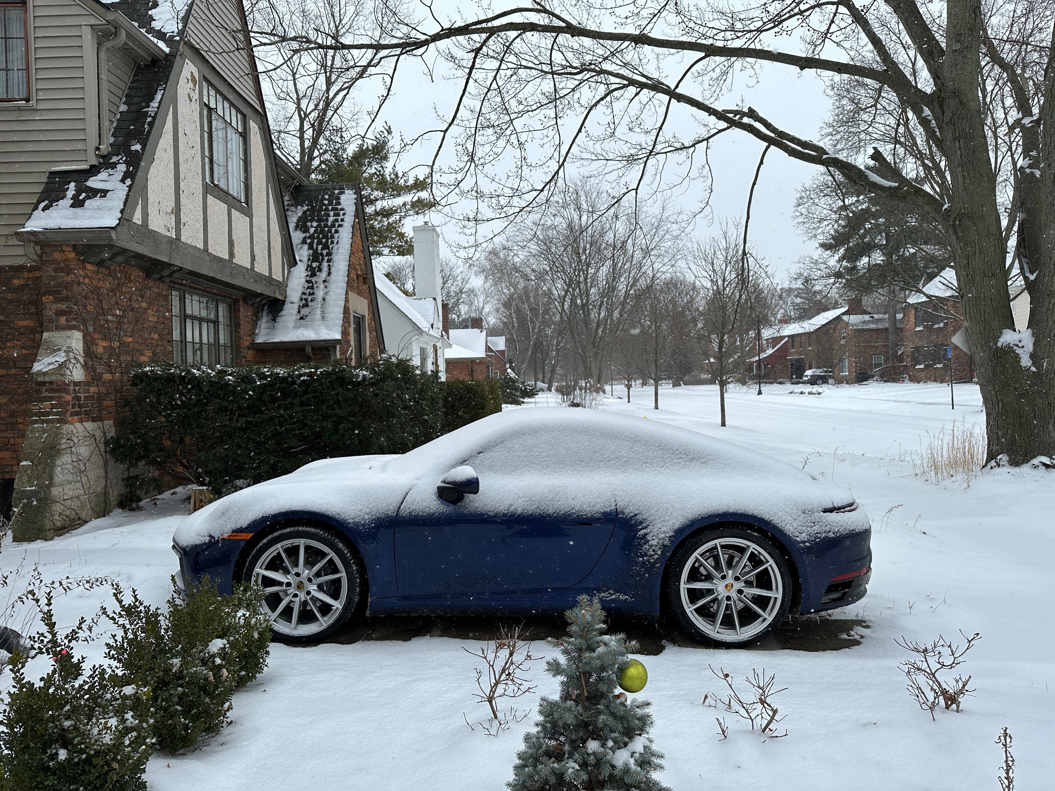 a blue 2023 porsche 911 carrera on a snow-covered road in michigan