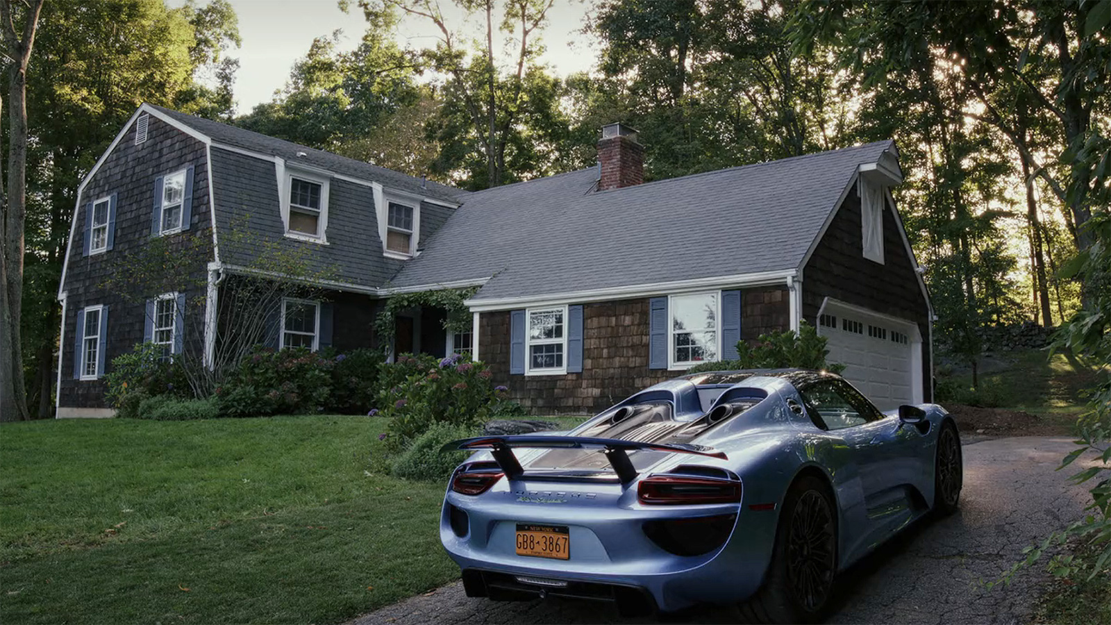 Rear-quarter view of Miles Bron's Porsche 918 Spyder parked in a driveway from Glass Onion: A Knives Out Story