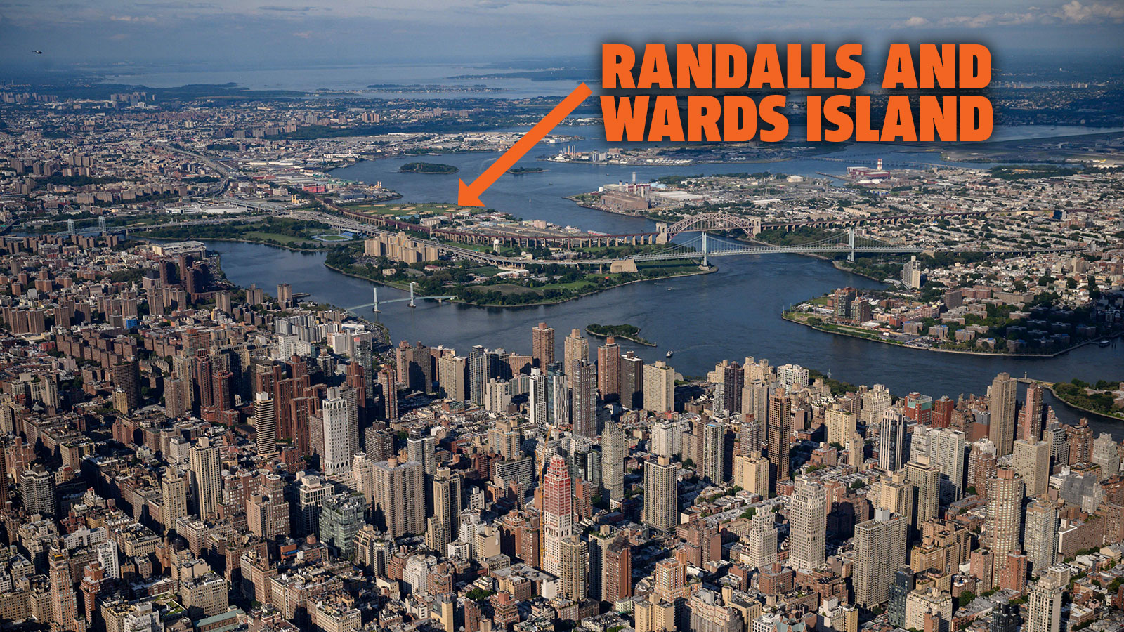 A photo of the New York skyline taken from above with an orange arrow pointing to Randalls Island in the East River. 