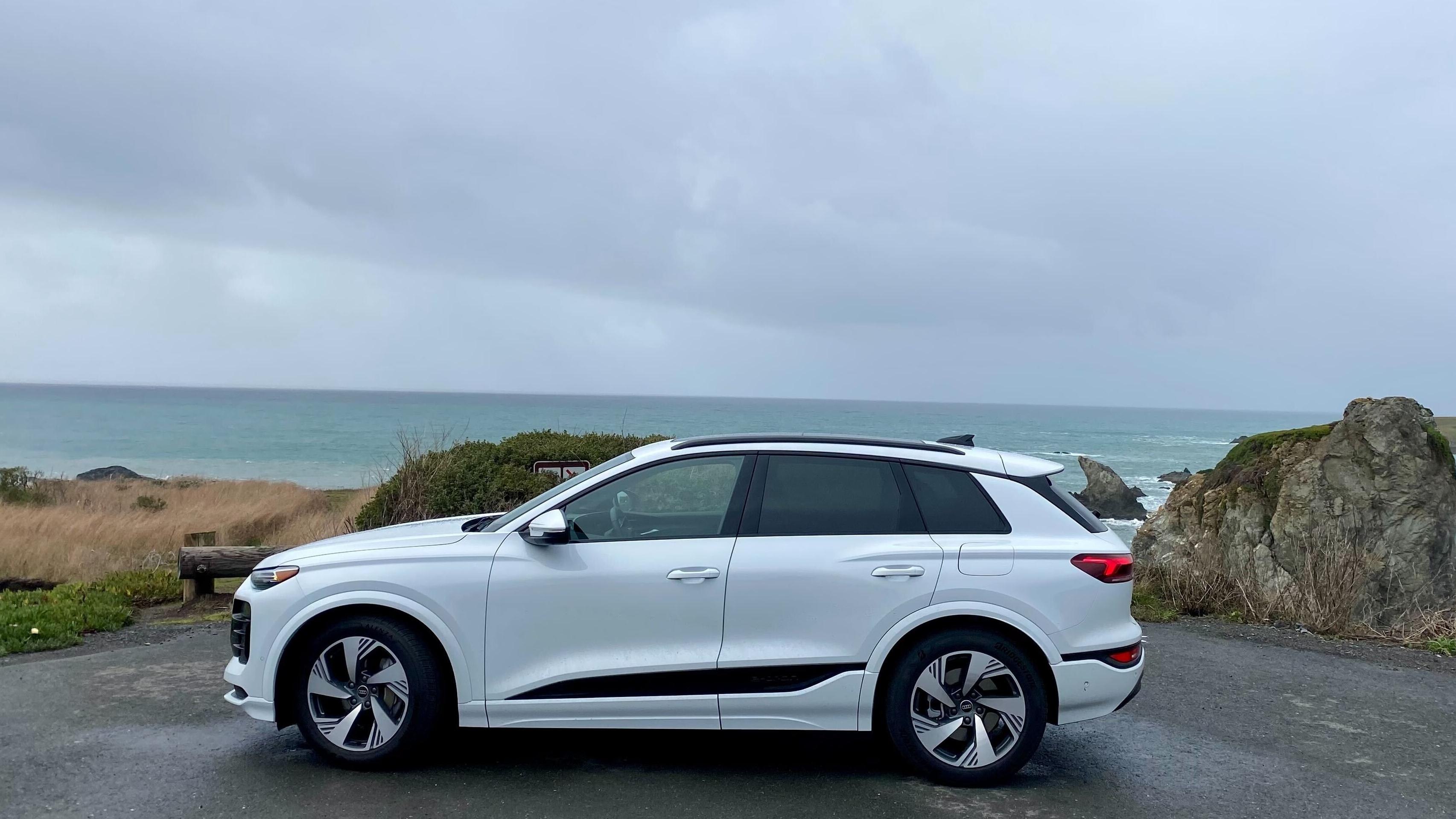 A side view of the white Q6 Quattro parked in front of rocks and the ocean