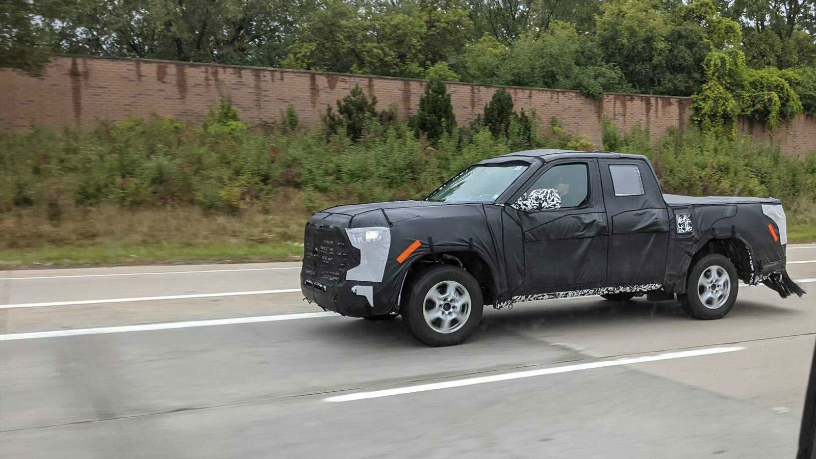 The Toyota Tacoma truck is disguised by a black wrap all over